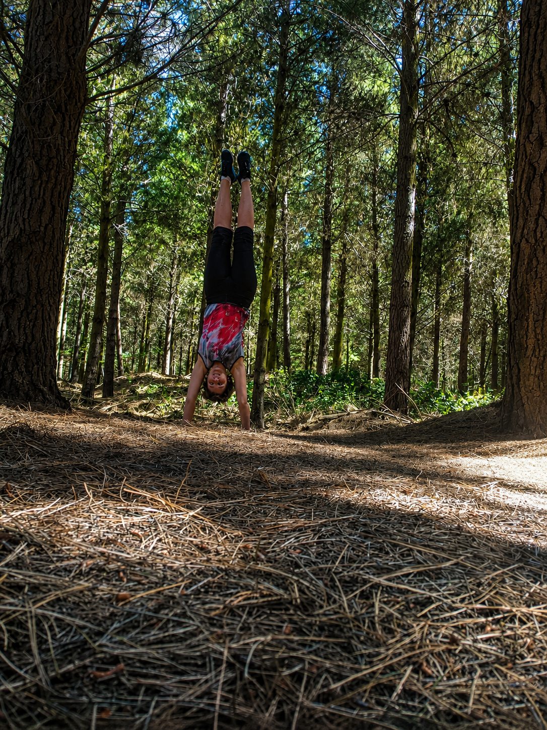 Hélène upside down in a handstand among the pines