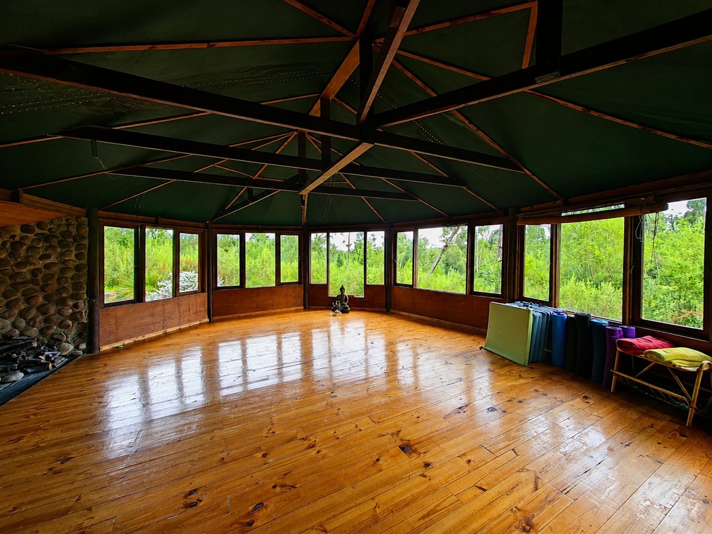 Inside the wooden yoga studio, windows on every side looking into the forest